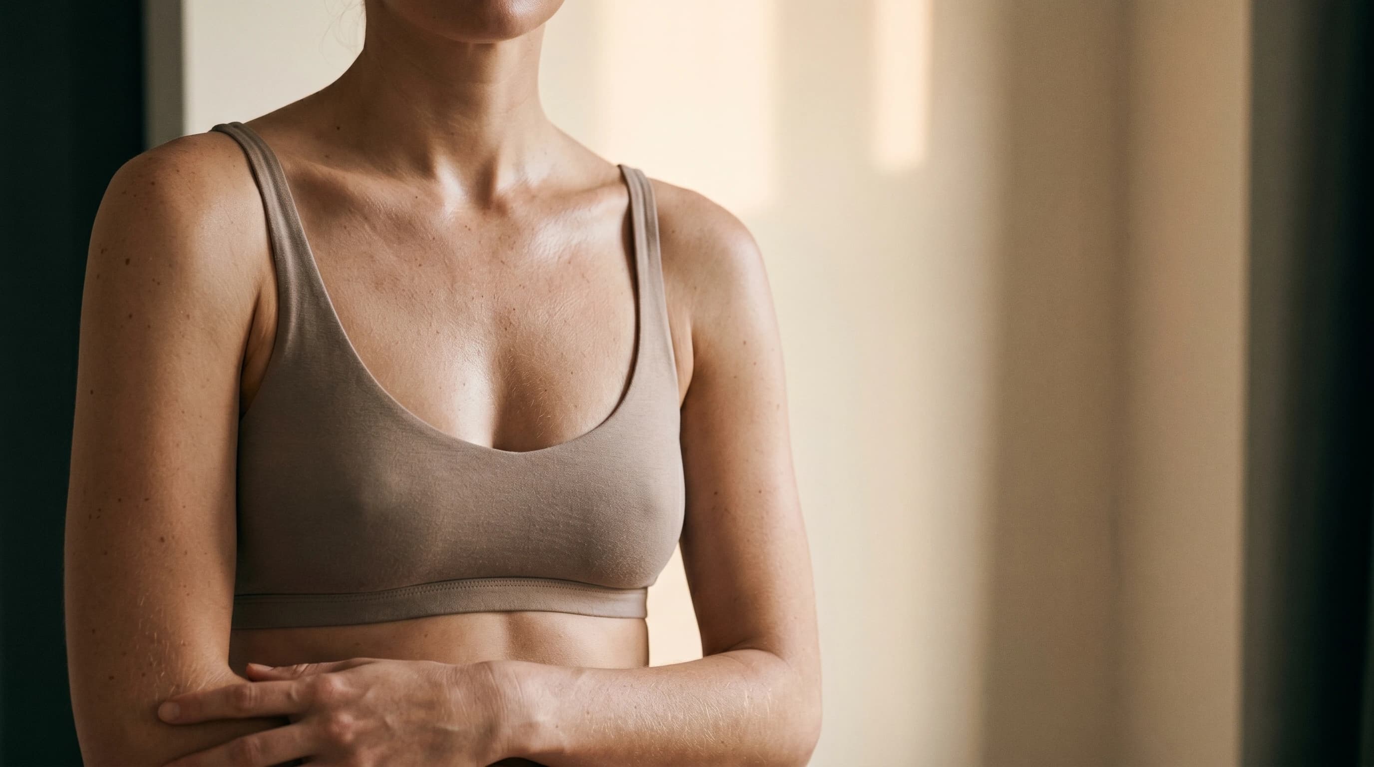 Body-Editorial: Décolleté in taupe Bralette in weichem Fensterlicht — Praxis Ästhetik am Isartor München