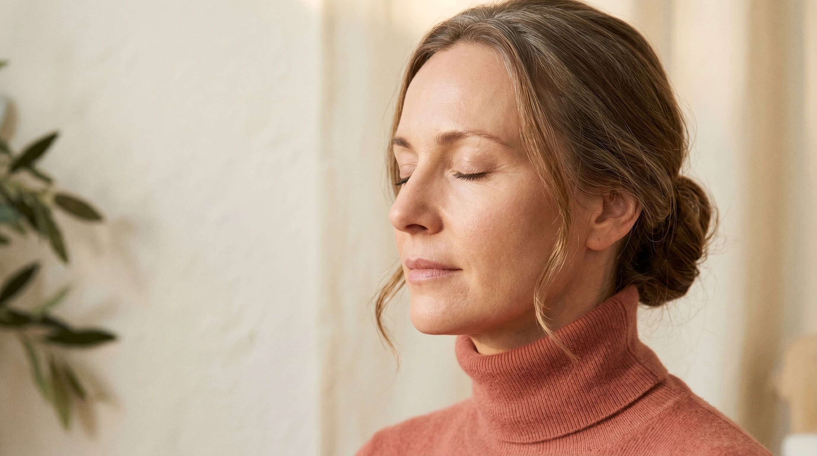Editorial Drei-Viertel-Profil mit ruhig geschlossenen Augen, dusty-coral Cashmere-Rollkragen — Praxis Ästhetik am Isartor München