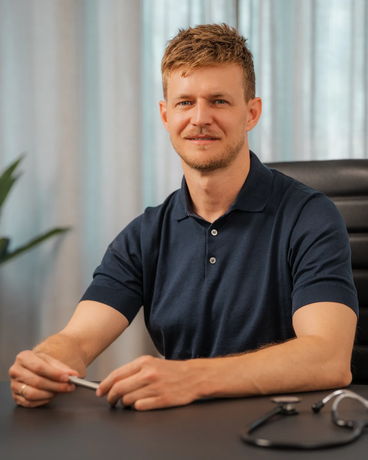 Dr. Fabian Weinschenk am Schreibtisch im Sprechzimmer der Praxis Ästhetik am Isartor München